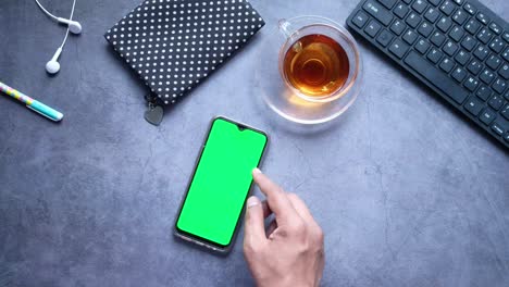 smartphone with green screen on a desk