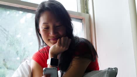 Happy-woman-using-mobile-phone-in-bedroom