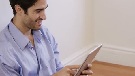 Man-sitting-on-floor-and-using-digital-tablet
