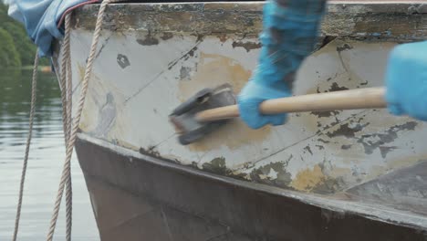 a carpenter sanding down a repair on a wooden boat hull