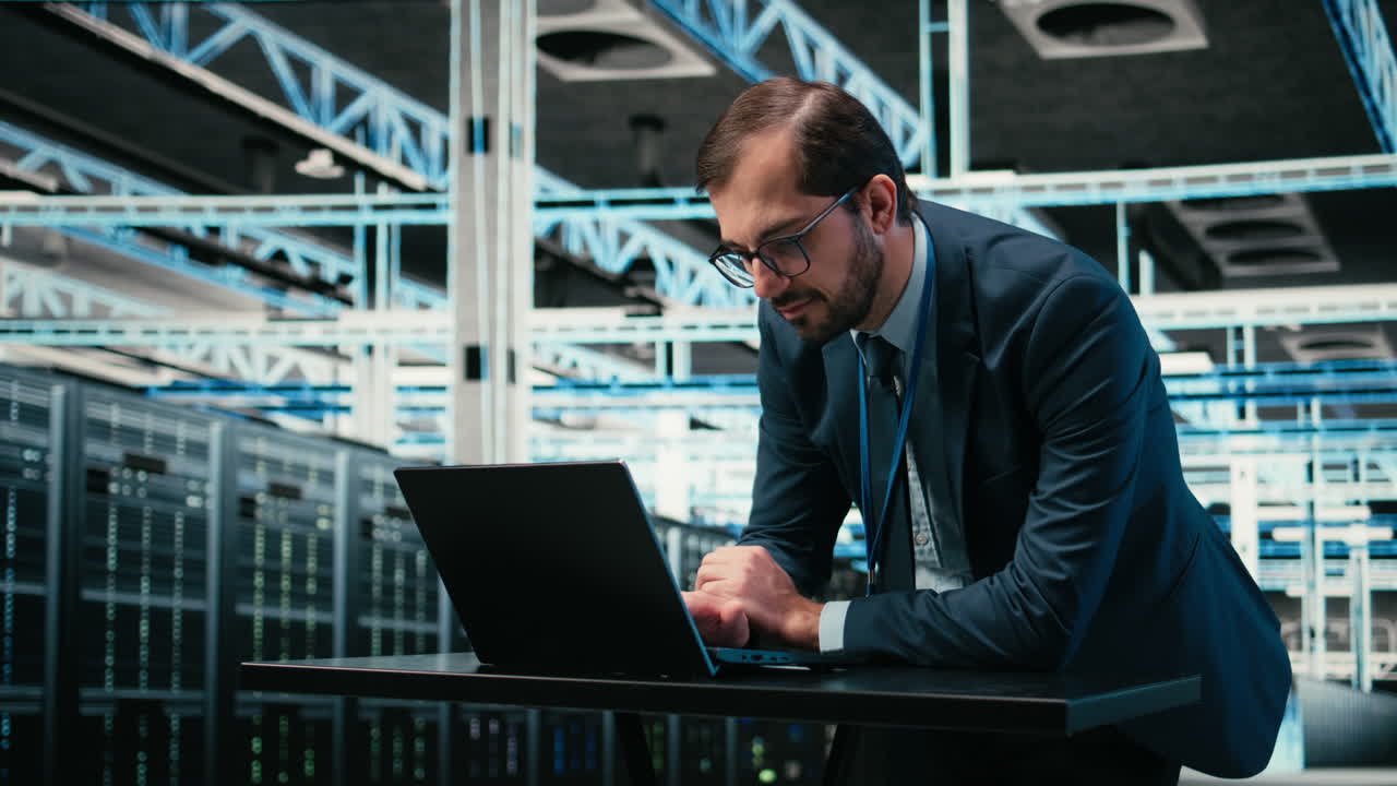 IT Professional Working on Laptop in a Modern Server Room