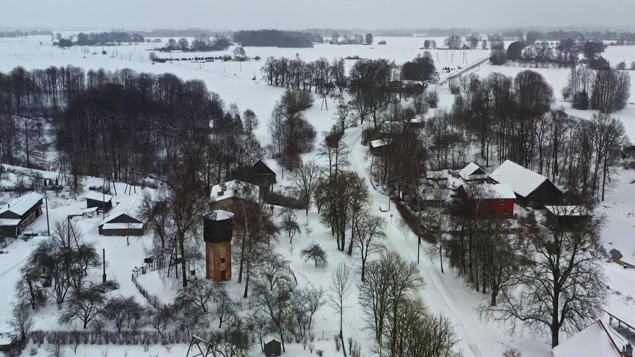 Pieni latvialainen kaupunki lumipeitteisine taloineen ja katuineen pilvisenä talvipäivänä, ilmakuva.