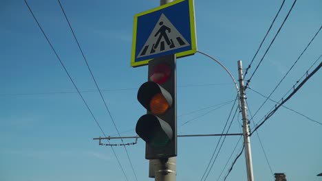 a blue and yellow colored pedestrian crossing signage on the post. -closeup shot