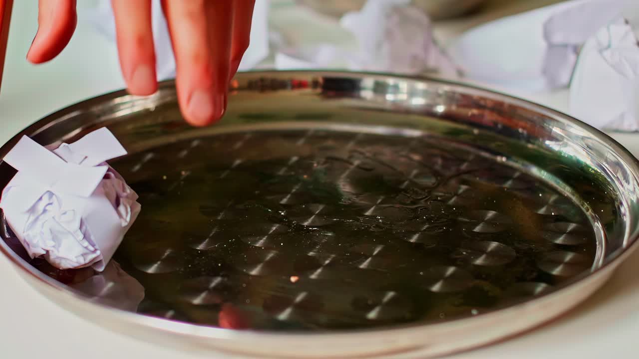 Empty metal tray surrounded by crumpled paper balls indoors