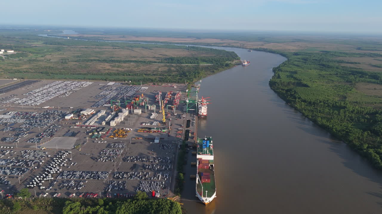Aerial view of commercial vehicle import port with cargo ships on Paraná River. Zarate, Buenos Aires, Argentina.
