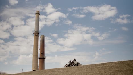 coal-fired power plant smoke stacks sit against a blue sky with scattered clouds