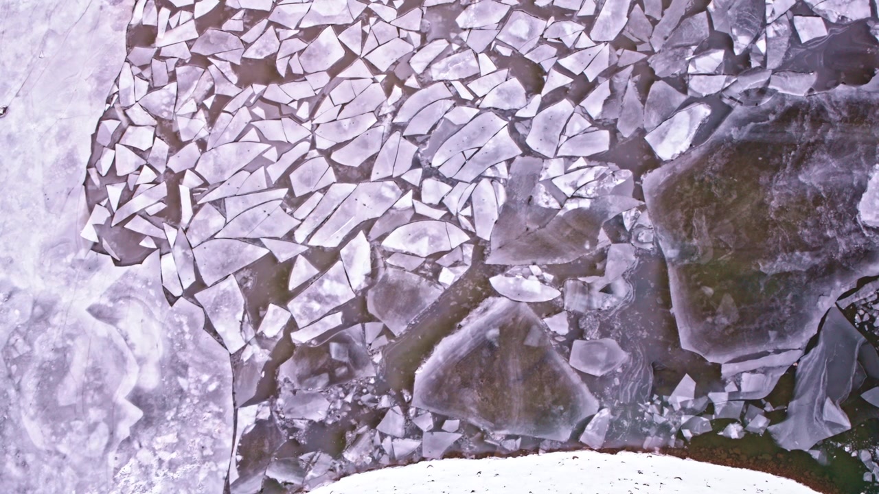 Tranquilla ripresa aerea di ghiaccio dei Grandi Laghi per lo più congelato con forme astratte sulla superficie.