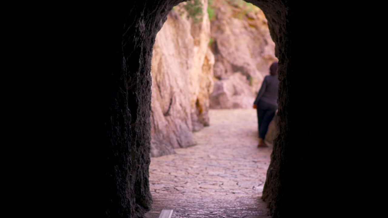 바위 가득한 산길 에 있는 터널 을 고 있는 여자