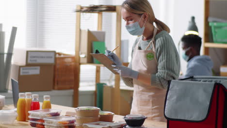 female worker in mask packing order at healthy meal delivery service