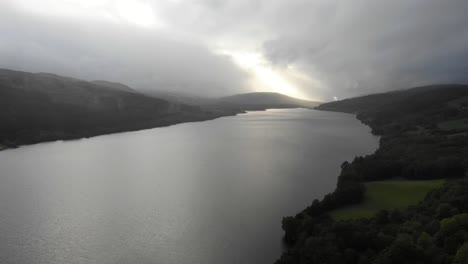 Luftaufnahme-Der-Ruhigen-Oberfläche-Von-Loch-Tummel-Mit-Bedeckten-Wolken-Und-Goldenem-Licht-Im-Hintergrund