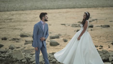 Wedding-couple-standing-near-mountain-river.-Groom-and-bride-making-faces