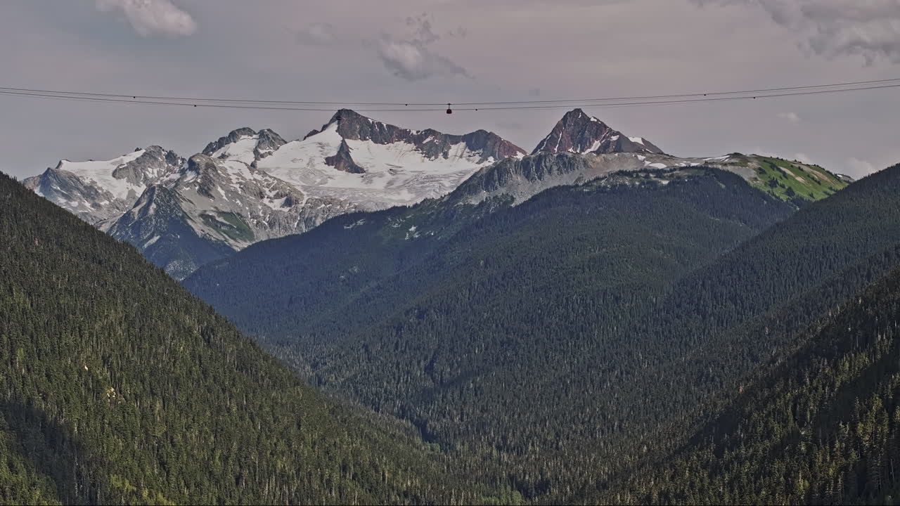 whistler bc canada aerial v8 drone flyover montaña boscosa capturando ascensor de góndola montando a través de valles verdes con cumbres cubiertas de nieve en el fondo - filmado con mavic 3 pro cine - julio 2023