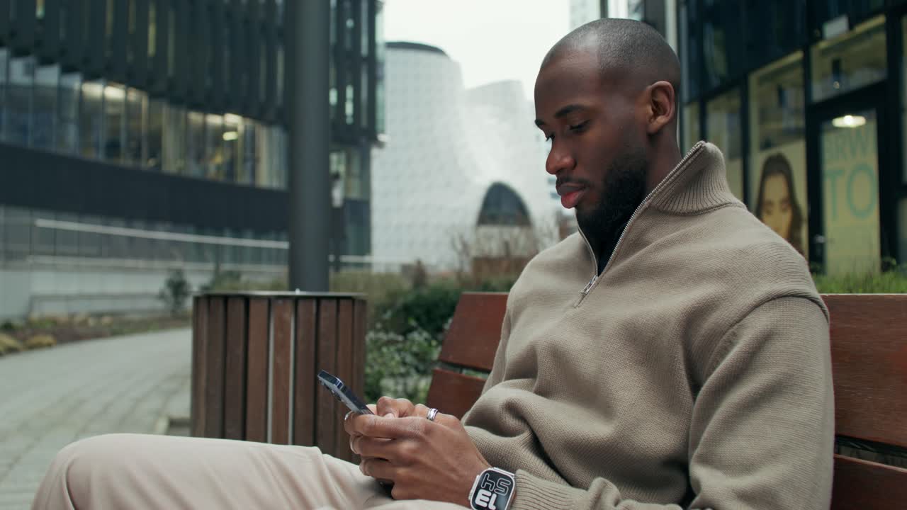 Man using smartphone on a bench in the city