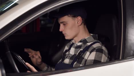 car repair service represanrarive using digital tablet to analyse all the main indicators of the vehicle he has to repair. sitting inside the car.