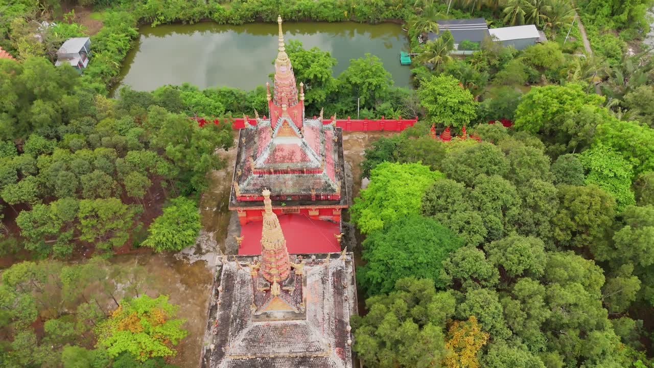 Cảnh quay từ flycam trên không của Chùa Botum Vong Sa Som Rong tại Sóc Trăng cho thấy các kiến trúc chùa, sân chùa màu đỏ, cây cối xung quanh và vùng nước gần đó tạo nên một cảnh quan văn hóa