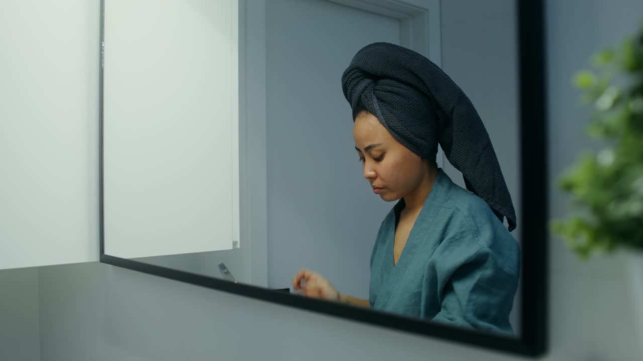 Donna che applica patch occhi al carbone in bagno