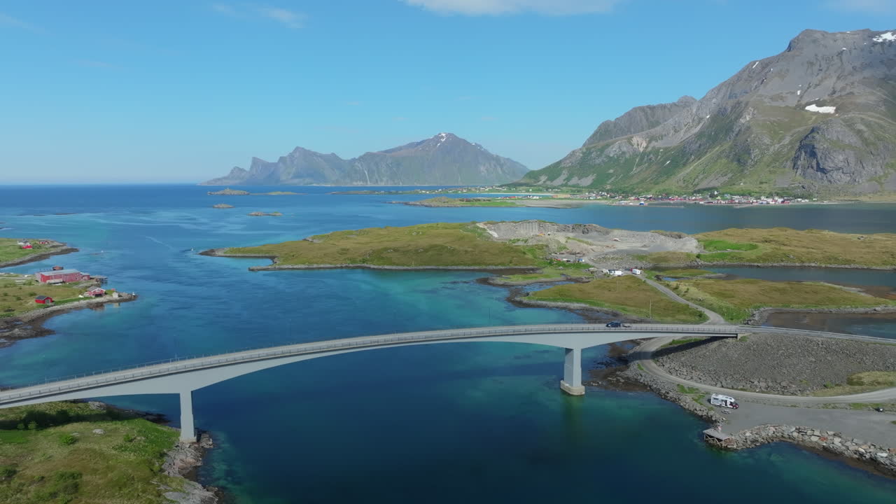 Scenic fjord landscape revealing Fredvang Bridges connecting Flakstadoya and Moskenesoya, featuring turquoise waters and dramatic mountain ranges in Lofoten archipelago