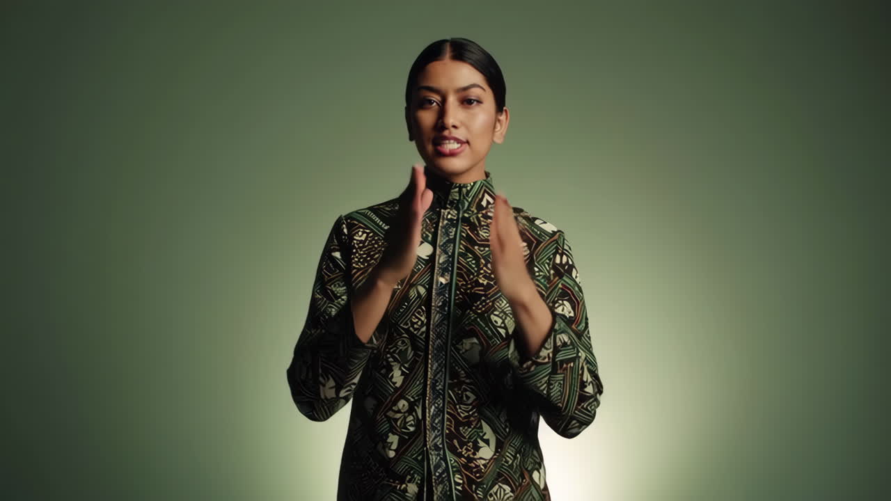 A woman in a patterned jacket gesturing and speaking in a studio