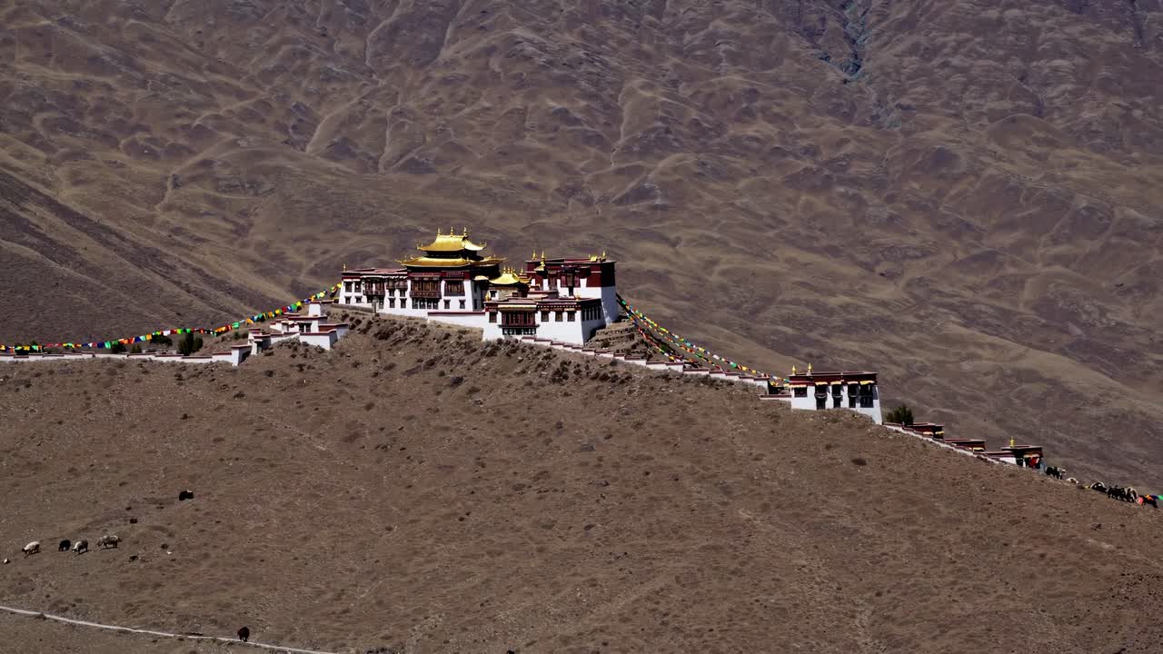 Aerial view of a monastery on a barren hillside, showcasing traditional architecture