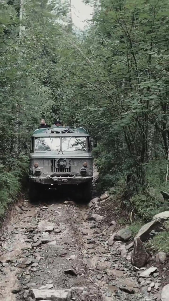 Robusto fuoristrada 4x4 affronta un sentiero sterrato e roccioso attraverso una fitta foresta di conifere sui monti Altaj, vicino a Gorno-Altaysk, nella Repubblica dell'Altaj, in Russia, mettendo in risalto i viaggi d'avventura in terre selvagge e remote
