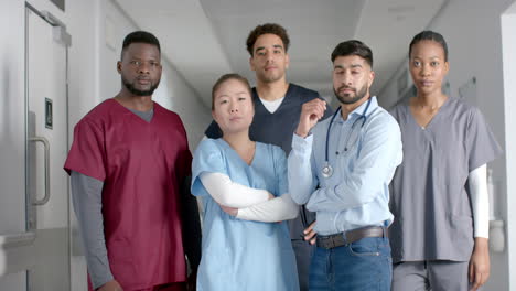 portrait of diverse male and female doctors wearing scrubs in hospital corridor, slow motion