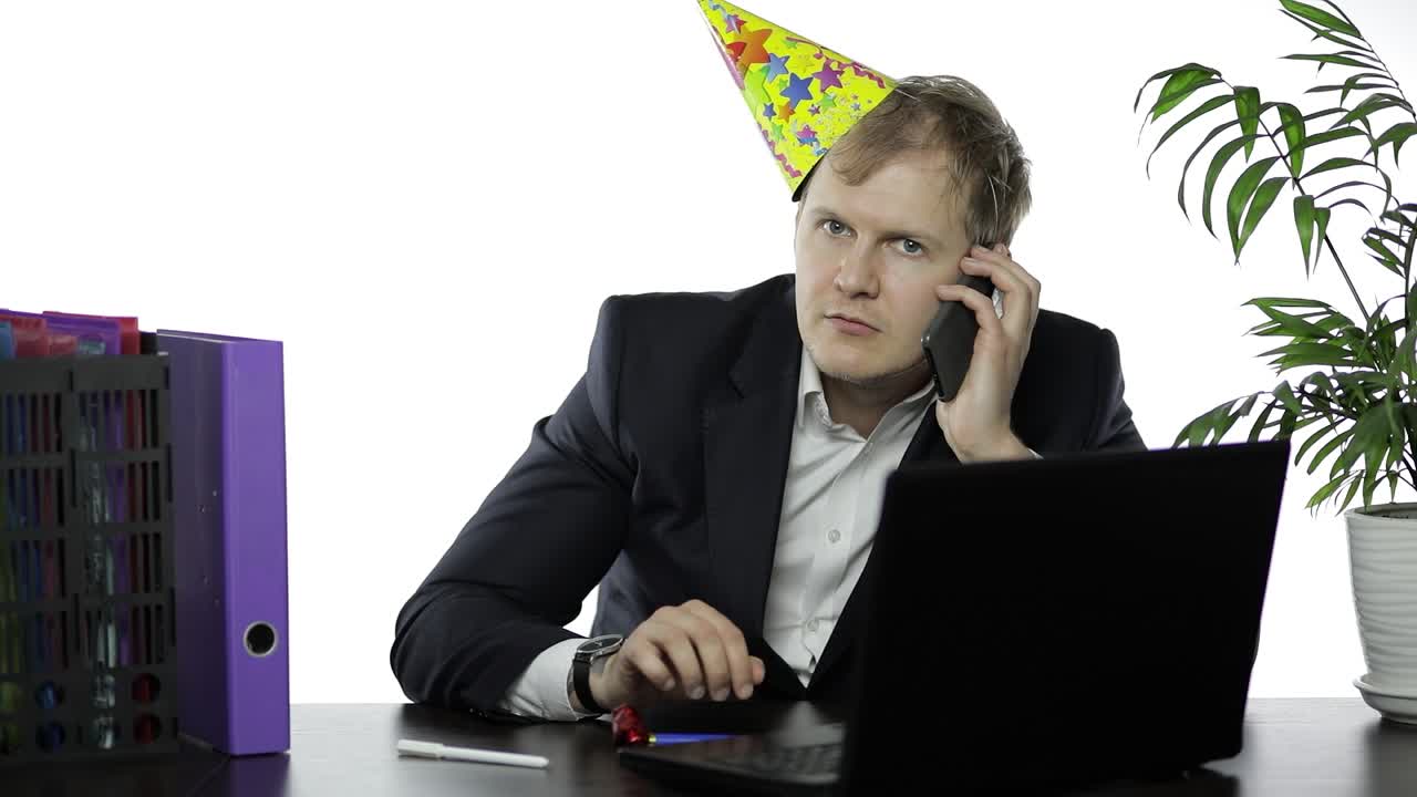 술에 취한 젊은 사업가 축제 모자를 휘두르고 전화로 이야기