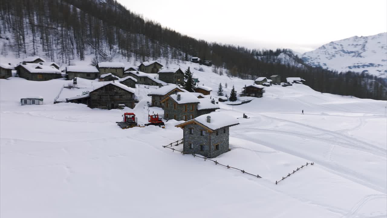 Aerial drone view of Cheneil, picturesque alpine village blanketed in snow, Stone houses, snow-covered roofs, forest backdrop, Italy