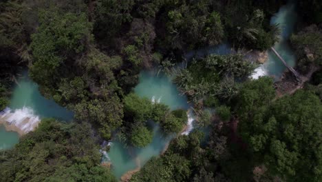 Cristal-clear-blue-water-river-in-the-middle-of-the-jungle-full-of-green-trees-in-Chiapas,-Mexico