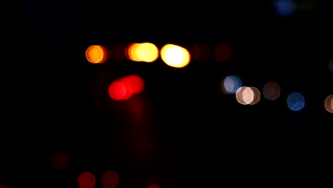 los círculos de bokeh en movimiento de las luces de los coches que corren por las calles de la ciudad. el fondo borroso de la ciudad, el tráfico nocturno.