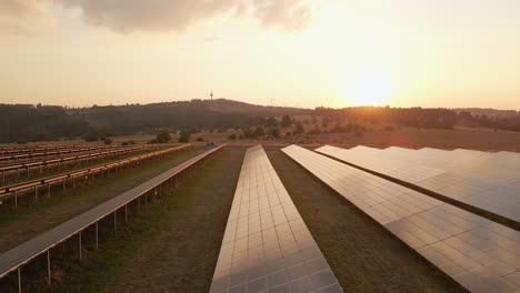 wide angle establishing shot of a beautiful sunset over photovoltaic panels of a solar farm in rural germany