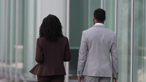 Back-view-of-two-people-wearing-suits-walking-near-office-building