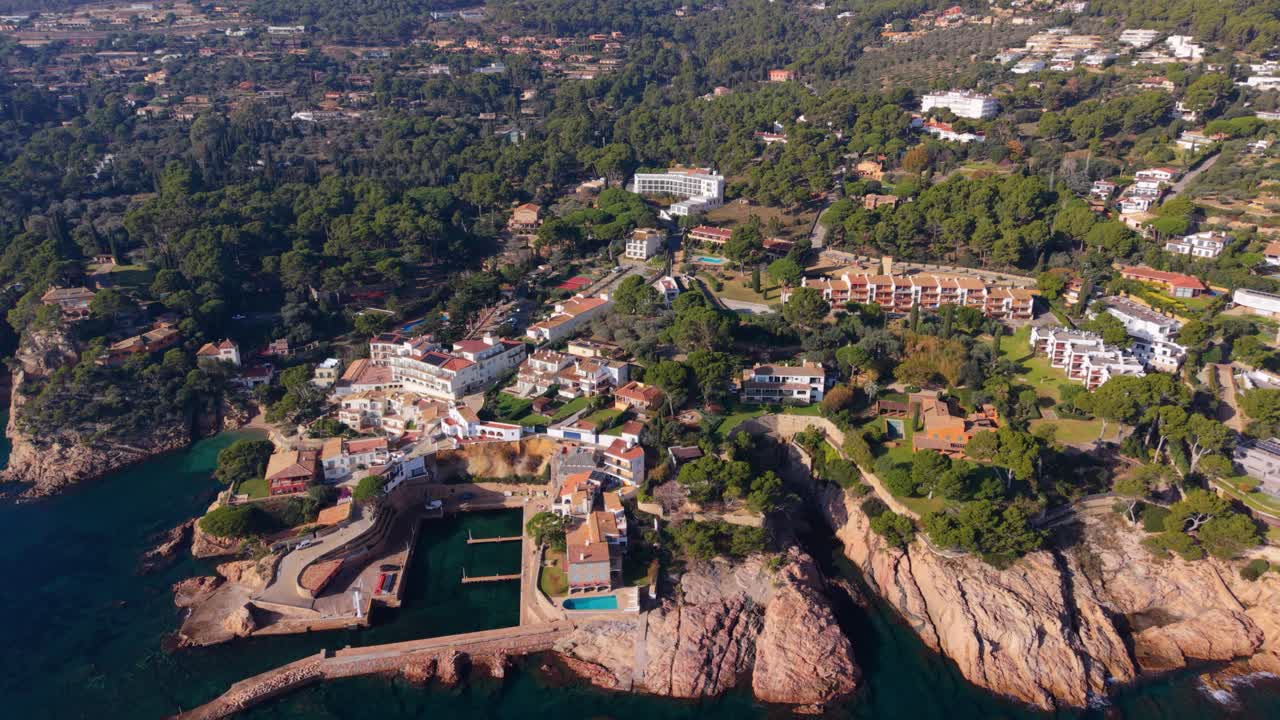 Stunning aerial perspective showing the picturesque coastal village of platja de fornells, nestled between rocky cliffs and clear turquoise waters on spain's beautiful costa brava