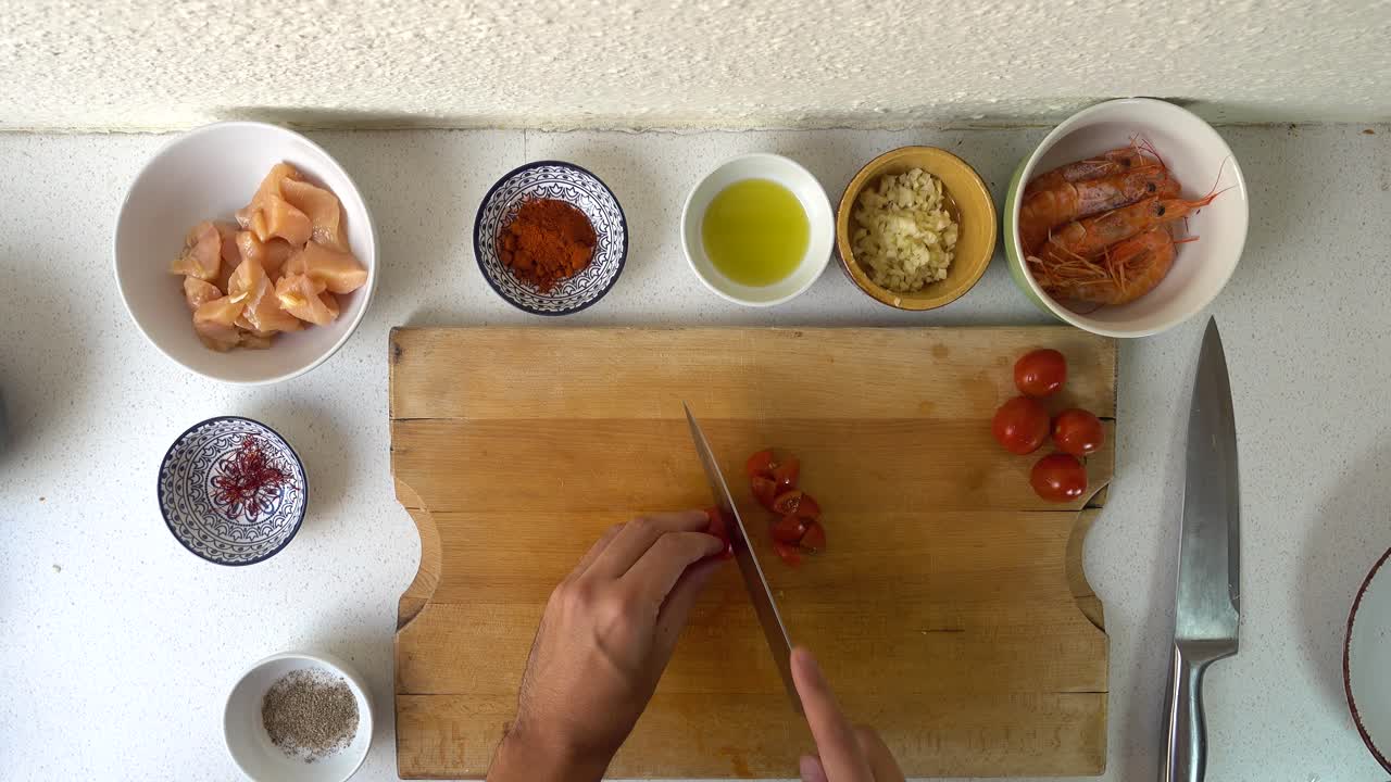 chef masculino manos cortando tomates en trozos pequeños en tabla de cortar de madera
