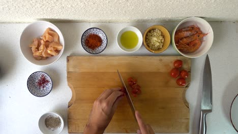 male chef hands cutting tomatoes into small pieces on wooden cutting board