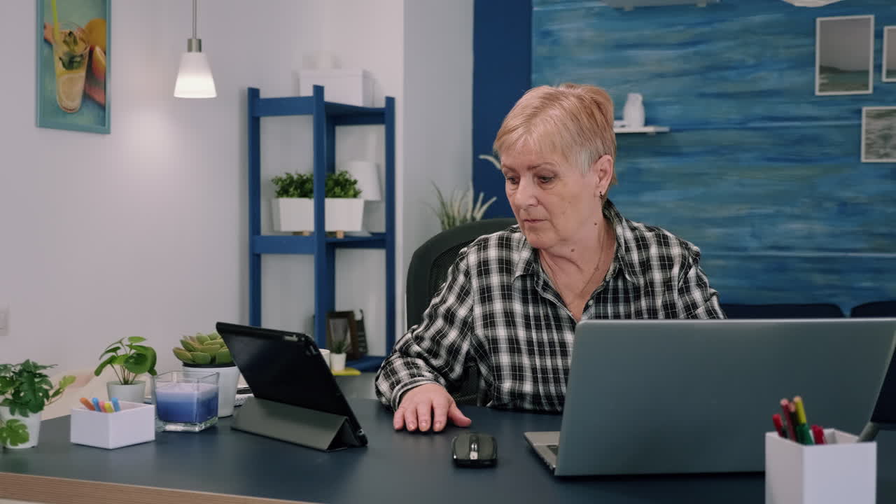 mujer madura usando tableta y portátil al mismo tiempo analizando gráficos financieros