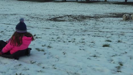 young girl in sled pulled by parent on snowy field slomo