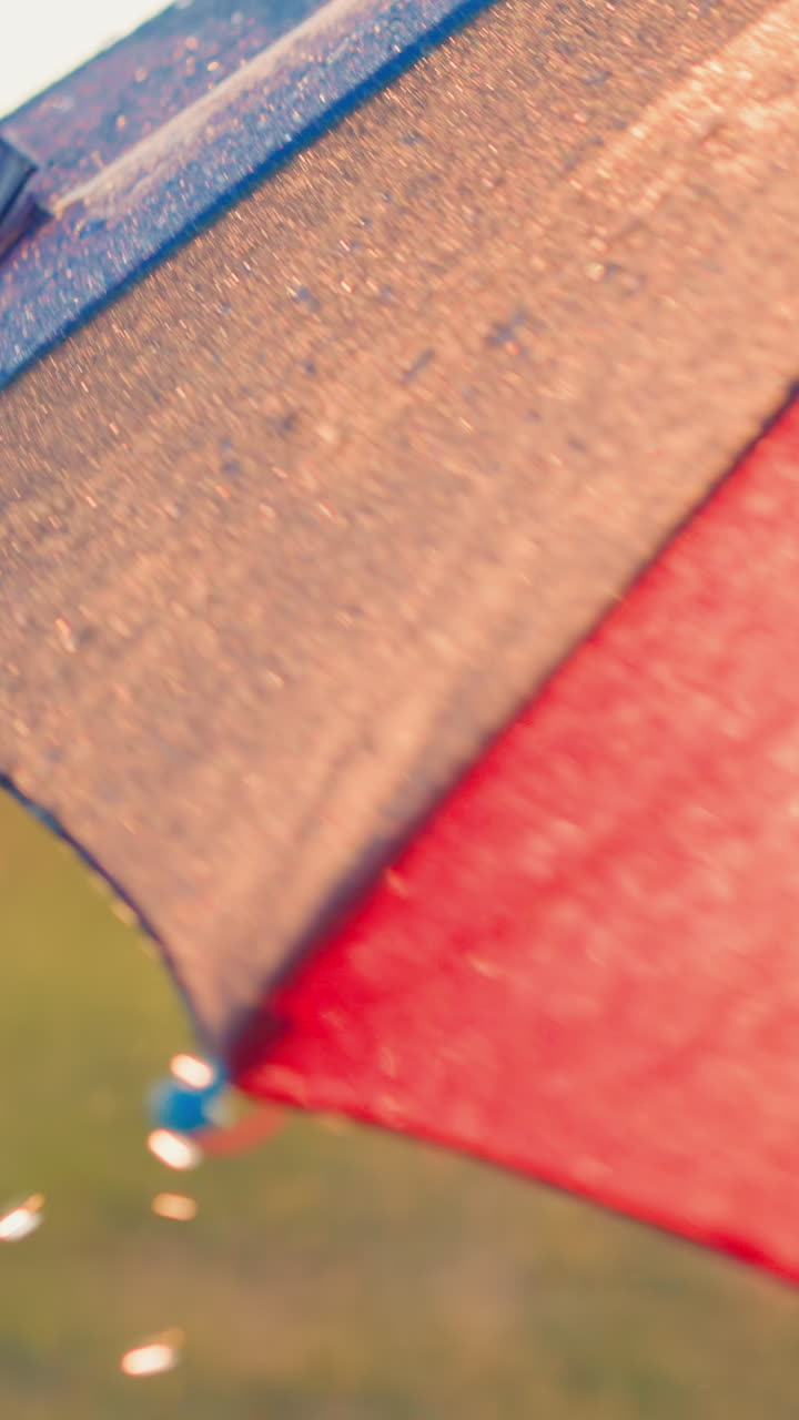 las gotas de lluvia crean una cascada con cada rotación. las gotas se derraman desde el colorido paraguas transformando el día de lluvia en una experiencia lúdica y encantadora.