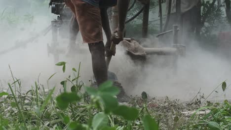 bore well drilling machine digging through soft stone while indian workman digs gravel out of the way slow motion