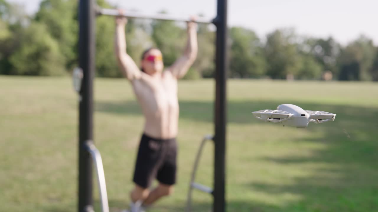 Focus on compact drone hover in air while male do pull ups, Czechia