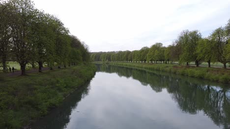 avenues of trees next to a river with straight paths in a park in cologne