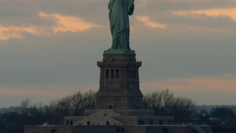 tilt up from liberty island to statue of liberty at sunset, center-framed