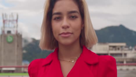 in the backdrop of tall buildings in port of spain, trinidad, a young hispanic girl walking on a rooftop wearing a red dress