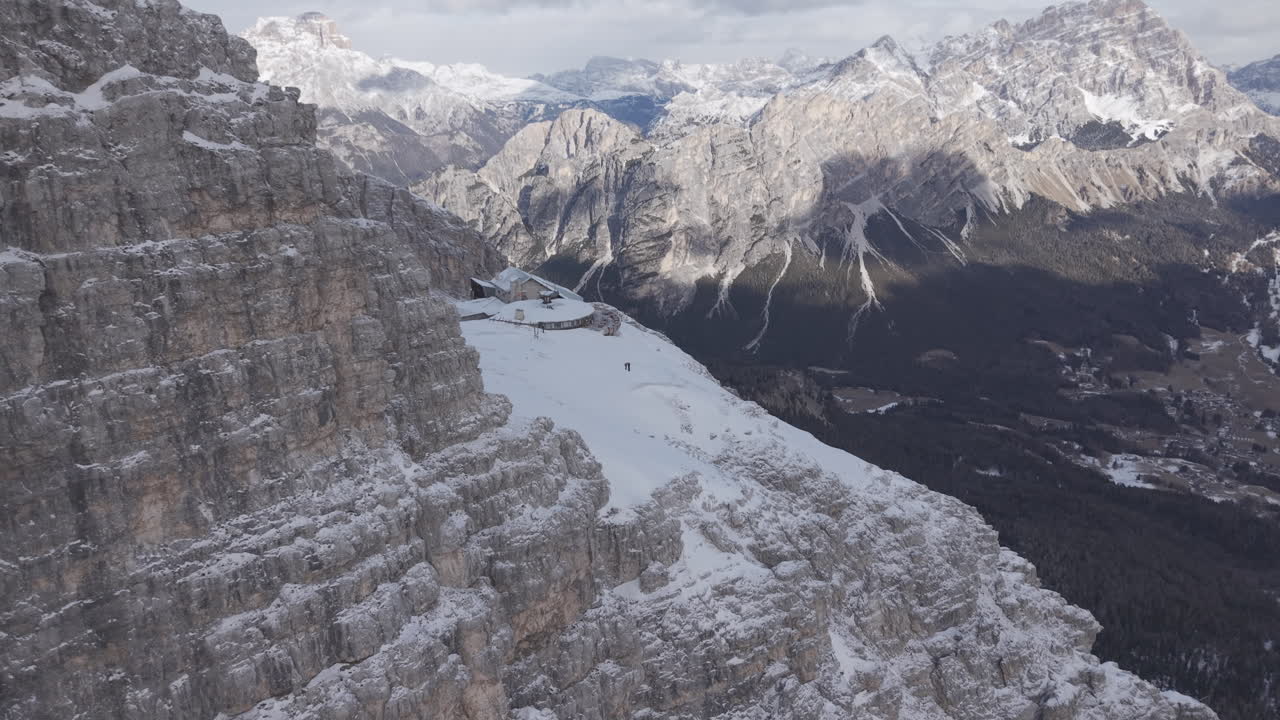 Ripresa aerea con drone di cime e pareti rocciose innevate delle Dolomiti sotto un cielo nuvoloso LOG