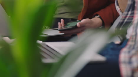 Nahaufnahme-Der-Hände-Einer-Geschäftsfrau,-Die-Im-Büro-Ihr-Smartphone-Nutzt-Und-Geschäftsideen-Beim-Brainstorming-Von-Kollegen-Zeigt,-Die-Am-Arbeitsplatz-Arbeiten