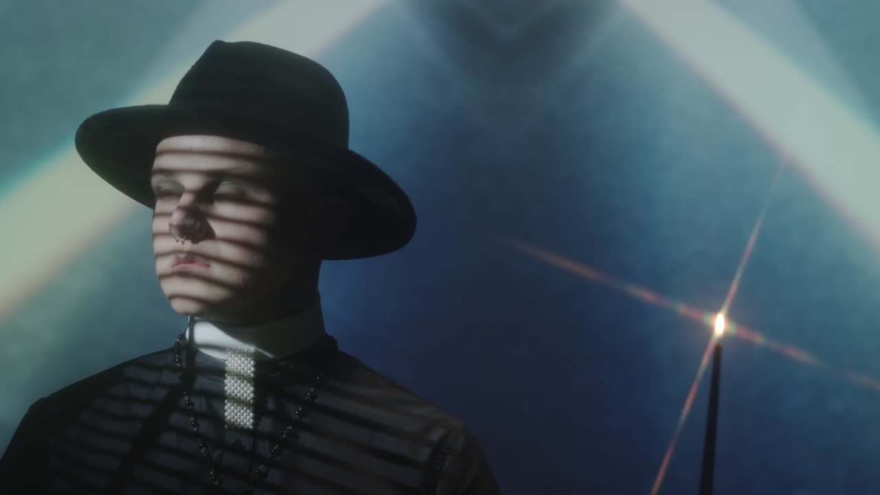 Priest Posing in Dark Room with Candle and Light Projection