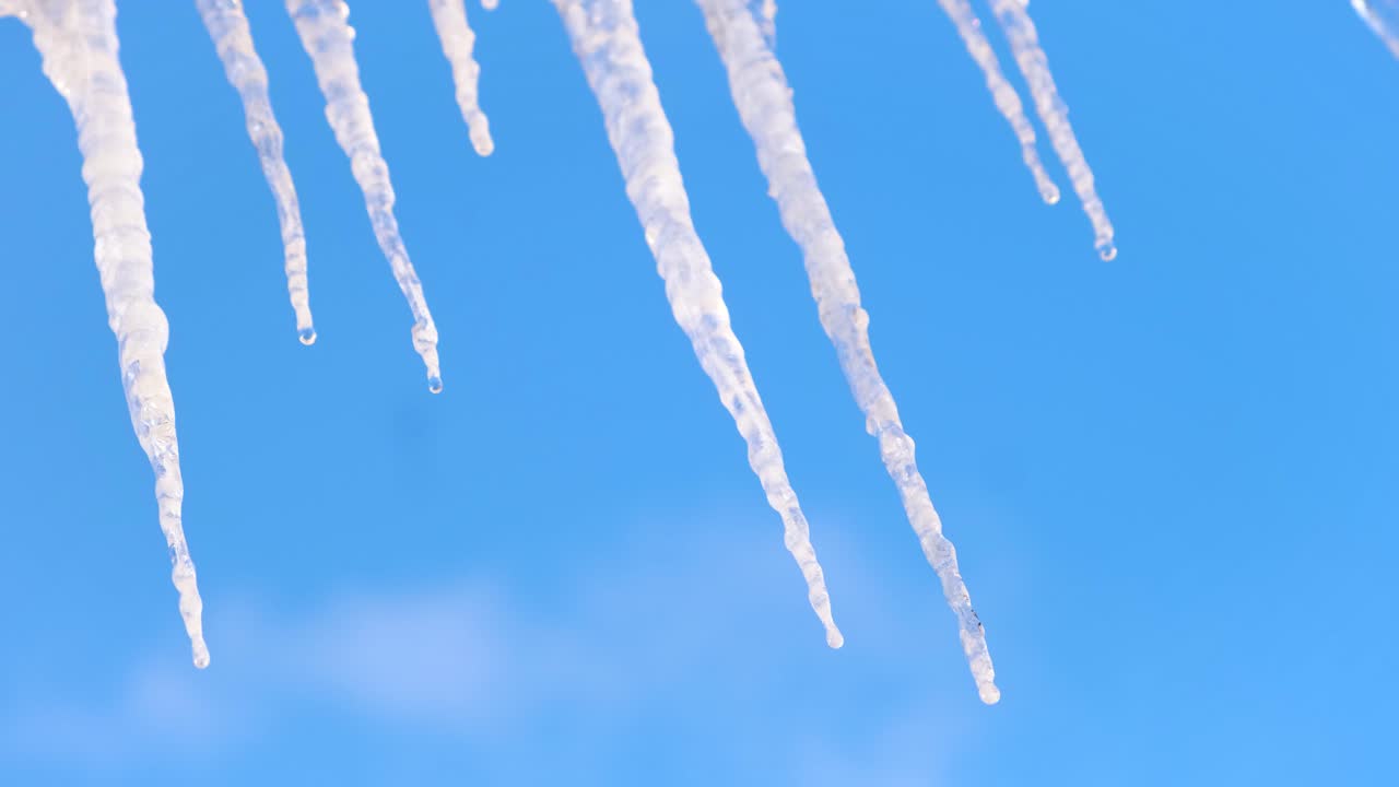 푸른 하늘을 배경으로 지붕에서 매달린 얼음