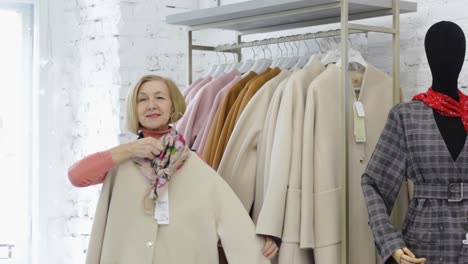 an elderly european woman chooses clothes in a store trying on herself. shopping and shopping