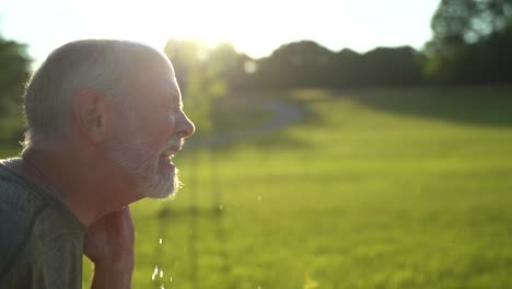 Slow-motion-sunny-scene-of-man-sneezing-showing-aerosol-using-water-hose