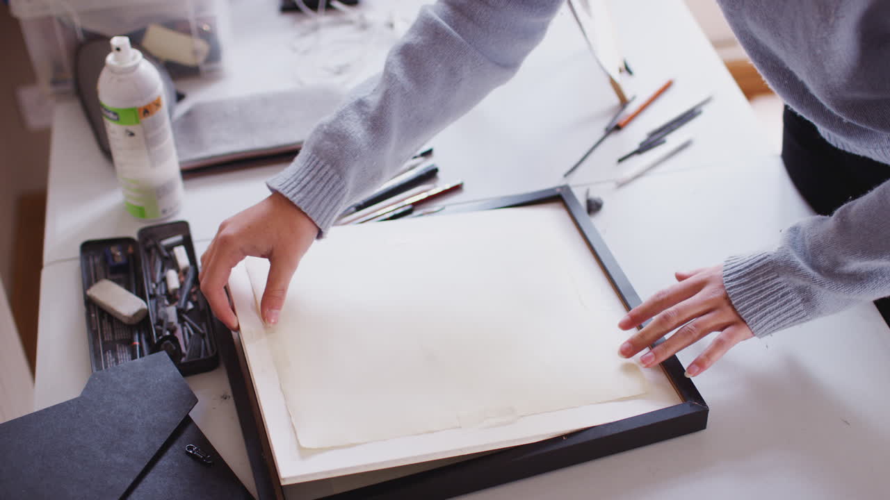 여성 십대 예술가 가 스튜디오 에서 개 의 프레임 된 나무 석탄 그림 을 들고 있다