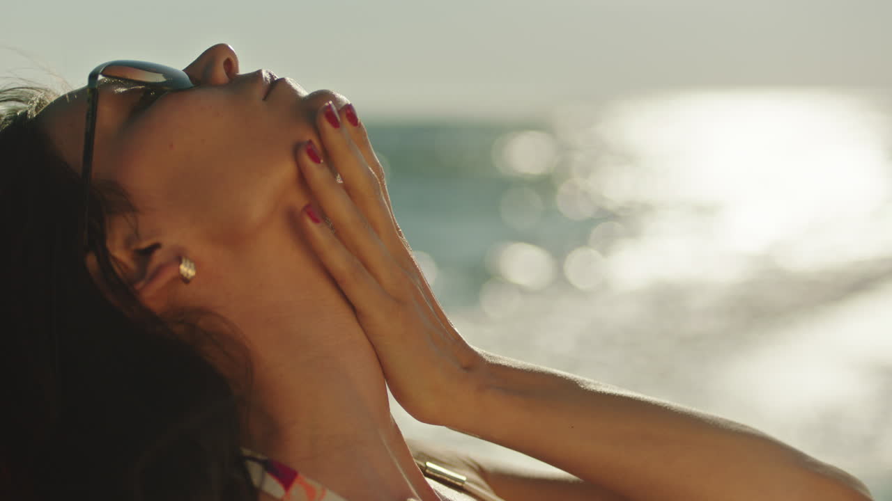 Woman Relaxing and Applying Sunscreen on the Beach